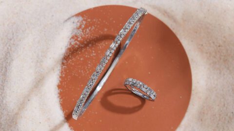 A diamond ring and an ear cuff in the sand.